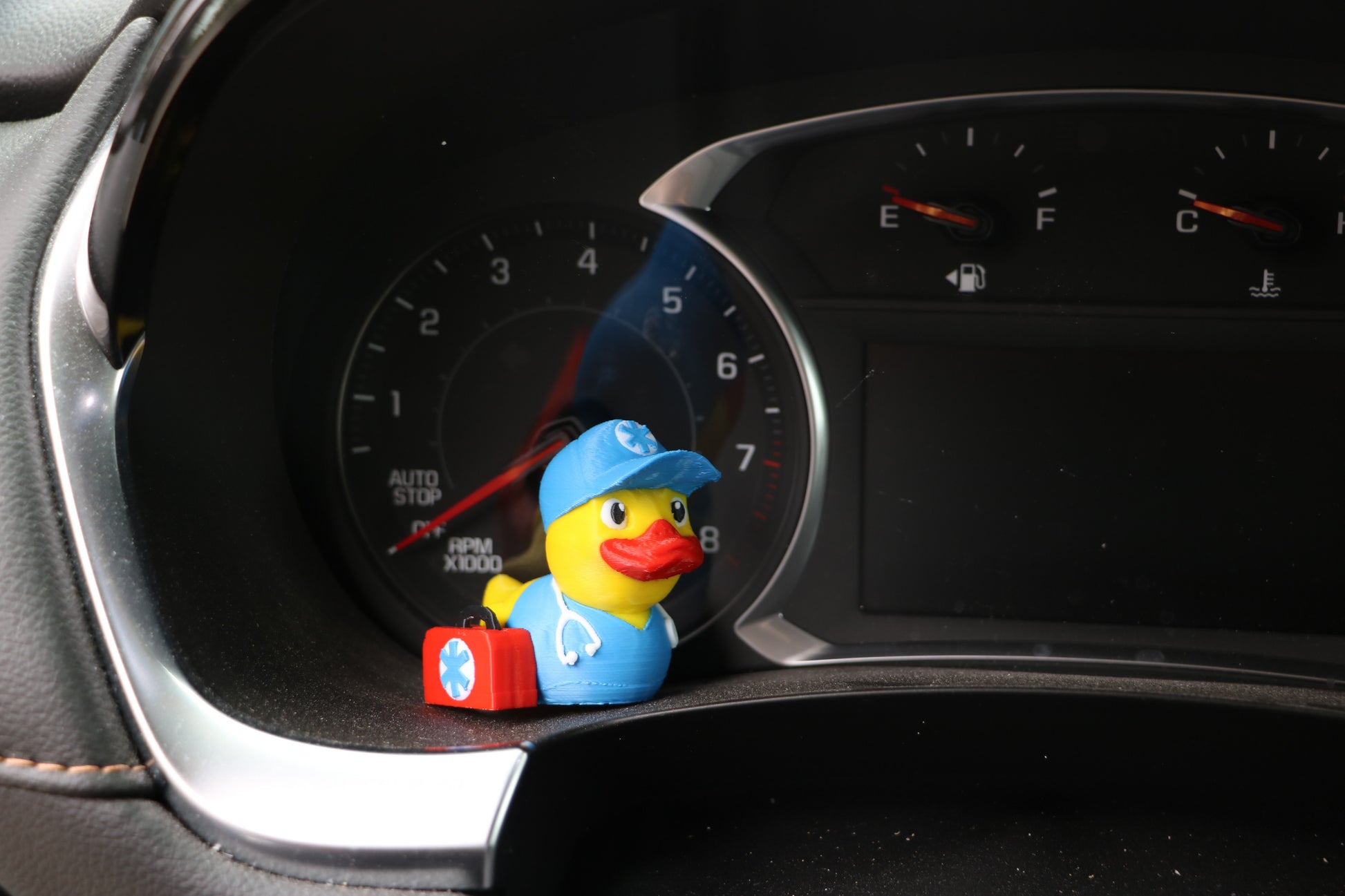 EMT Duck sitting near the instrument panel on a car's dashboard